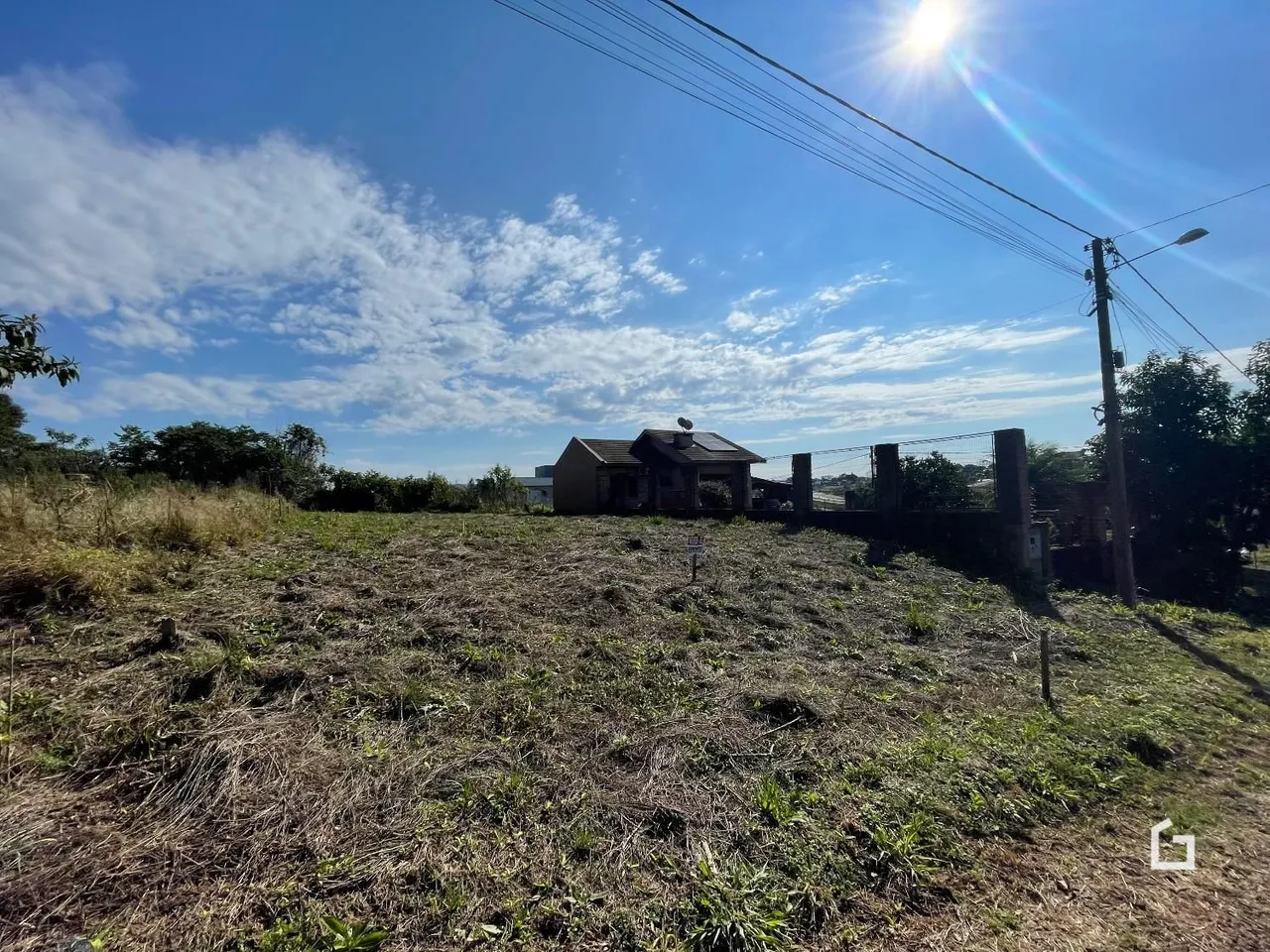 Vista externa de uma propriedade com vegetação seca no primeiro plano.