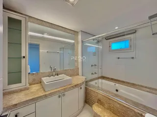 Banheiro com bancada e box de vidro em um imóvel.