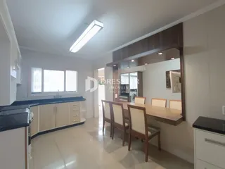 Interior de uma cozinha com armários e mesa de jantar em um imóvel.