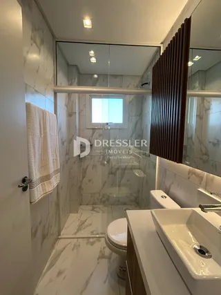Foto de um banheiro com revestimento em mármore branco e louças sanitárias brancas.
