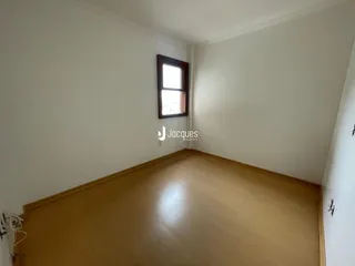 Vista interna de uma sala com piso de madeira e paredes brancas.