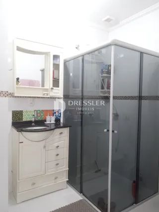Banheiro com armário branco e box de vidro transparente.