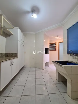Interior de uma cozinha com revestimento de cerâmica branca e armários brancos.