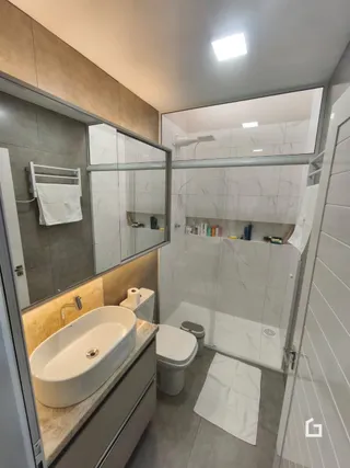 Foto de um banheiro interno com louças sanitárias brancas e piso de cerâmica.