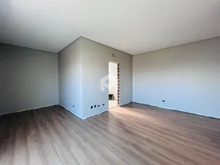 Ambiente interno de uma sala com piso de madeira clara e paredes cinzas.