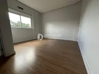 Sala de estar com piso de madeira clara e grande janela.