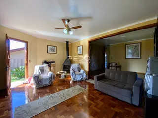 Sala de estar com piso de madeira e lareira em uma residência.