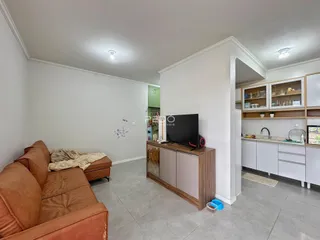 Sala de estar com sofá e cozinha integrada em apartamento.
