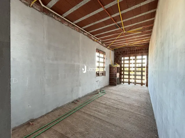 Vista de um corredor interno com paredes brancas e teto de tijolos exposto.