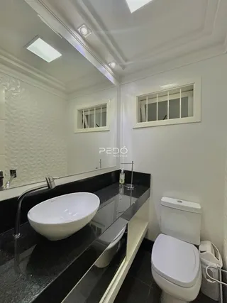 Foto de um banheiro moderno com bancada escura e vaso sanitário branco.