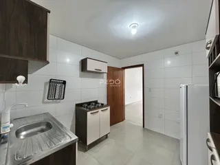 Cozinha com armários escuros e piso claro em ambiente interno.
