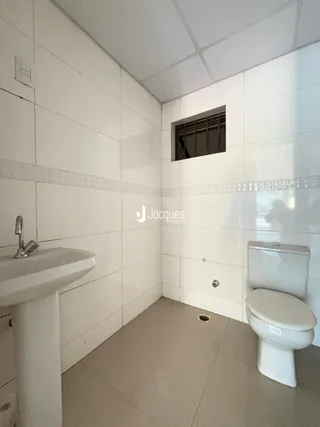Foto de um banheiro com revestimento branco e piso claro.