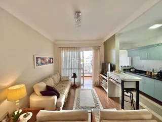 Sala de estar com sofá e piso de madeira em um imóvel no Brasil.