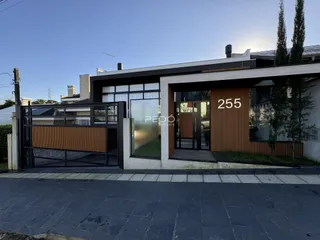 Fachada de uma residência em Lajeado, Brasil, com portão de ferro e grandes janelas.