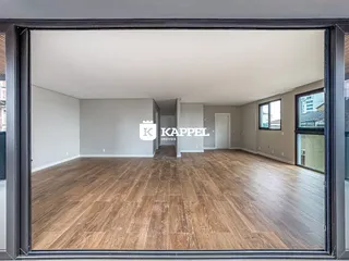 Ambiente interno de uma sala ampla com piso de madeira clara.