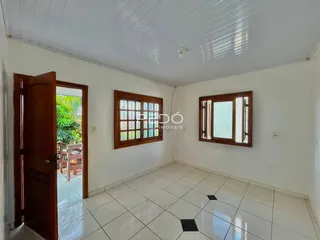 Sala de estar com piso de cerâmica e janelas de madeira.