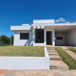 Fachada externa de uma casa branca com gramado e calçada em Lajeado.