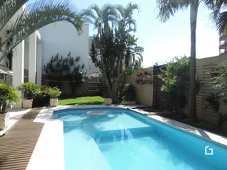 Foto da piscina externa com vegetação tropical.