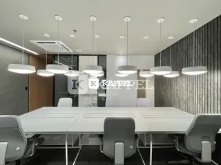 Uma sala de reuniões moderna com mesa longa e cadeiras em um ambiente com painéis escuros.