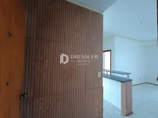 Parede de revestimento marrom com porta de madeira e abertura para um ambiente claro.