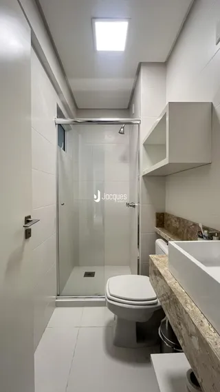Foto de um banheiro com box de vidro e revestimento branco.