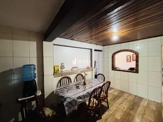 Vista interna de uma sala de jantar com piso de cerâmica e teto de madeira.