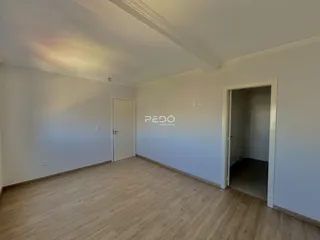 Sala de estar com piso de madeira clara e paredes brancas.
