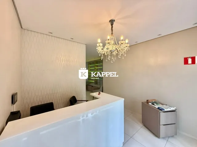 Ambiente interno com balcão branco e lustre de cristal em um espaço moderno.