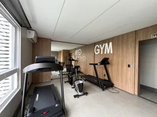 Uma sala interna com equipamentos de ginástica e revestimento de madeira nas paredes.