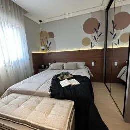 Quarto com cama e cortinas claras em um imóvel.
