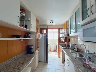 Vista interna de uma cozinha com armários brancos e bancadas de granito.