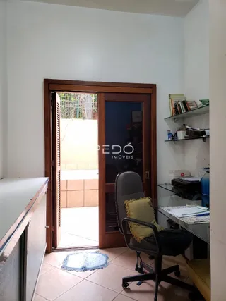 Vista interna de um corredor com porta de madeira que leva a uma área externa.