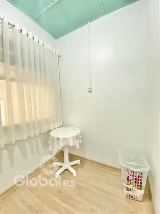 Interior de um cômodo com parede branca e piso de madeira clara.