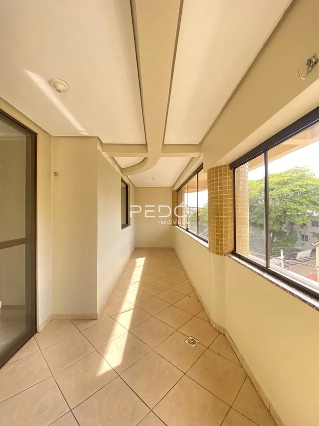 Corredor interno com piso de cerâmica e janelas amplas.