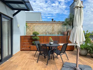 Área externa com mesa e cadeiras em um pátio com vista para uma piscina.