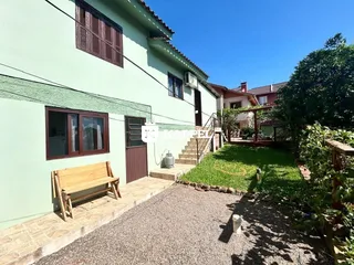 Fachada de uma casa verde em Lajeado, Brasil, com jardim e calçada.