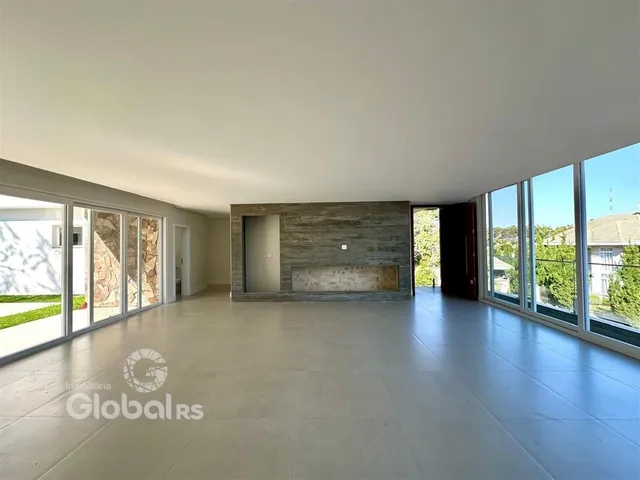 Ambiente interno de uma sala ampla com piso claro e grandes janelas.