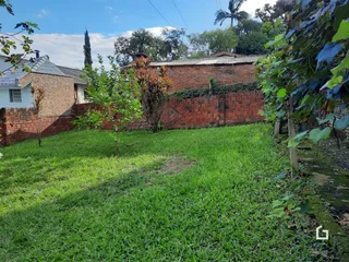 Vista do quintal com gramado e muro de tijolos de uma propriedade em Lajeado.
