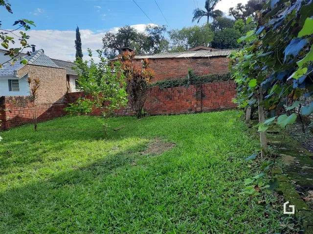 Vista do quintal com gramado e muro de tijolos de uma propriedade em Lajeado.