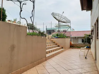 Área externa pavimentada com degraus e muro de contenção.