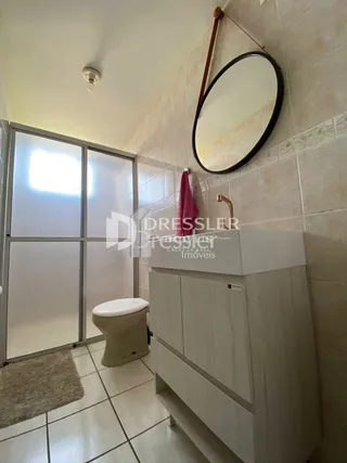 Foto de um banheiro com azulejos claros e um espelho.