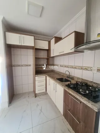 Cozinha moderna com armários brancos e bancada de mármore.