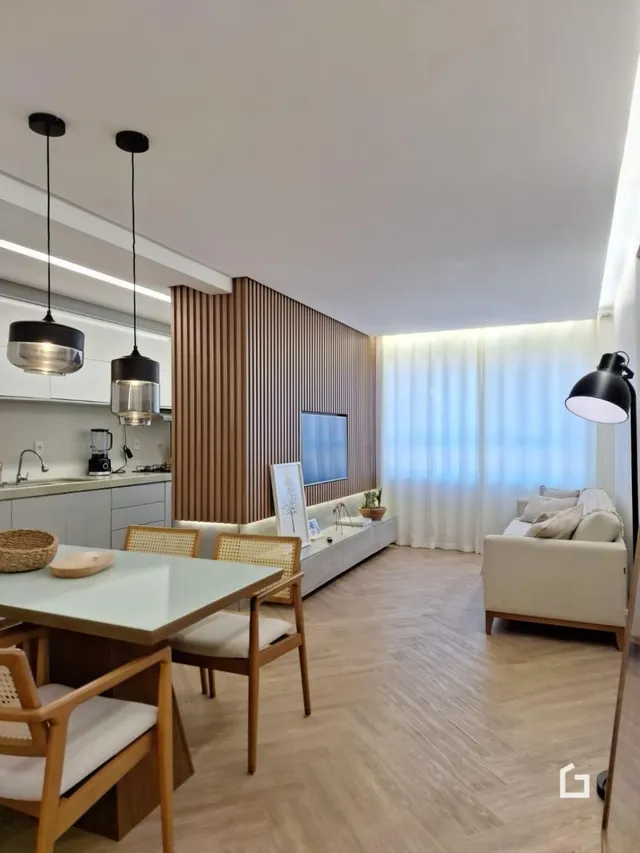 Sala de estar com mesa de jantar e piso de madeira clara.