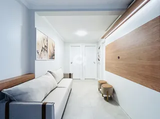 Sala de estar moderna com sofá cinza e painel de madeira na parede.