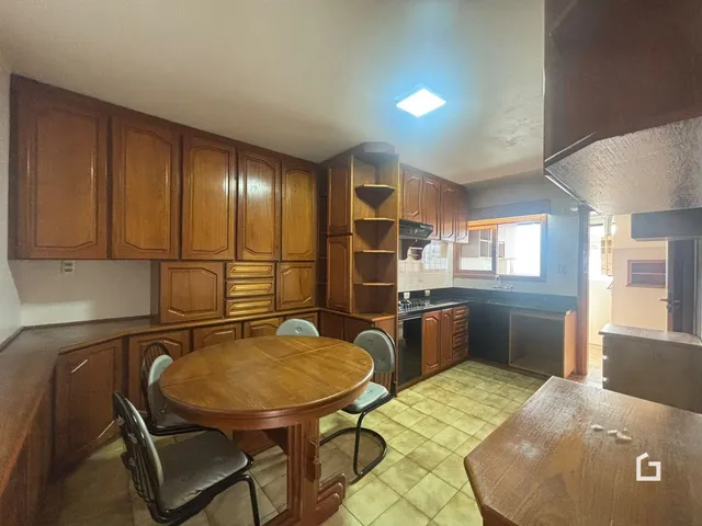 Ambiente interno de cozinha e jantar com armários de madeira e mesa de jantar.