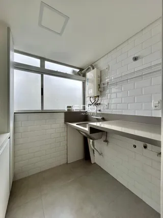Interior de um ambiente com revestimento de azulejos brancos e bancada.