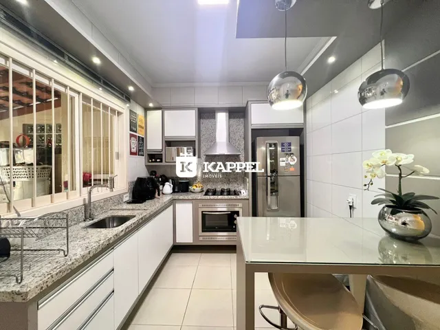 A cozinha moderna apresenta armários brancos e bancadas de granito.