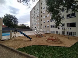 Área externa com equipamento de playground e gramado em um lote residencial.
