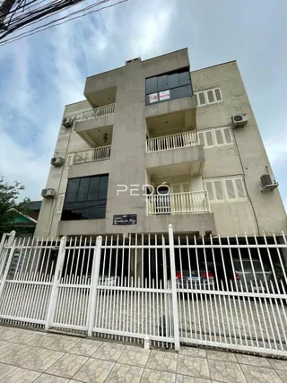 Fachada de um prédio residencial em Lajeado, Brasil, com cerca branca na frente.