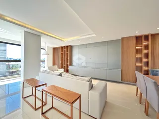 Sala de estar moderna com sofá e mesas de madeira em um apartamento.